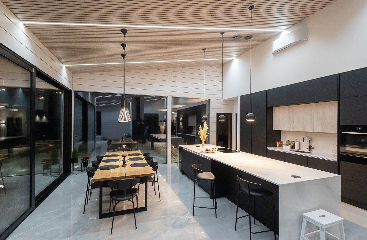 L'illuminazione a strisce LED per la cucina, installata nelle scanalature del soffitto, è versatile e regolabile. L'immagine mostra una fresca illuminazione neutra